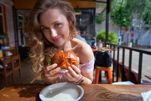 Piękna biała kobieta jedząc pyszne hamburgery w słoneczny dzień — Zdjęcie stockowe