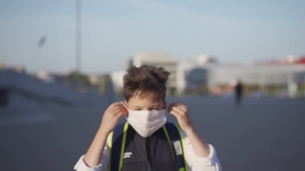 Un colegial caucásico que se pone mascarilla. Estudiando durante la pandemia de Covid-19. Regreso al concepto escolar — Vídeos de Stock