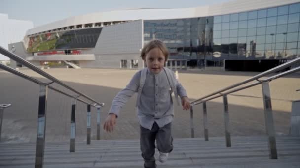 Écolier avec sac à dos courir en haut à l'école pour les leçons à la journée ensoleillée. Vue de face — Video