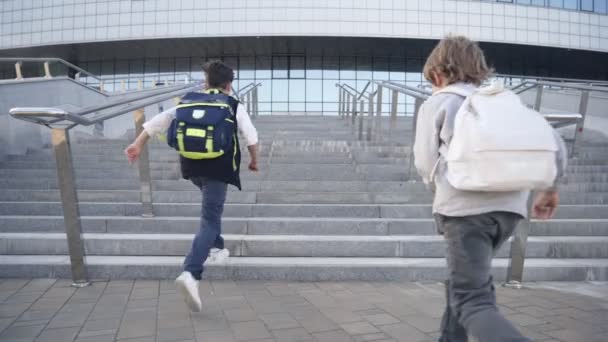 Schoolkinderen met rugzakken rennen naar school voor lessen. Achteraanzicht — Stockvideo