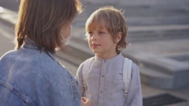 Anne oğluna okula kadar eşlik eder. Bir anne okula girmeden önce oğlu için koruyucu bir maske takar. Okul yılının başlangıcı.