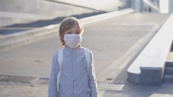 Glada skolpojkar i medicinsk mask möts på skolgården och hälsar på sina armbågar efter coronavirusepidemin. Unga killar och nytt liv i covid-19 eller coronavirus. Social distansering tillsammans koncept — Stockvideo