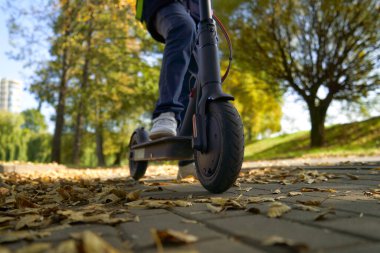 Sırt çantalı öğrenci okula elektrikli scooterla gidiyor..