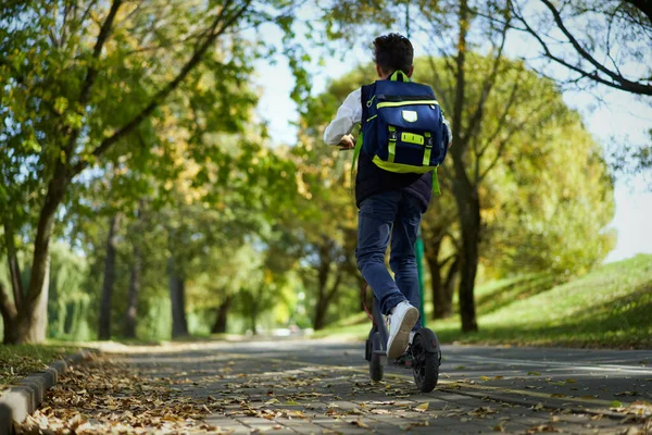 Sırt çantalı öğrenci okula elektrikli scooterla gidiyor..