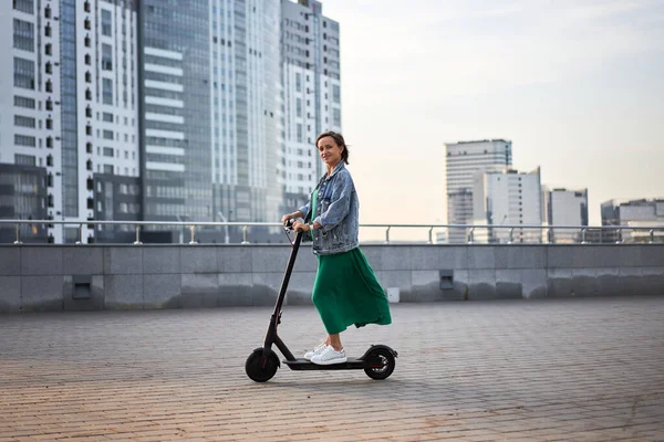 Carefree young woman riding an electric scooter in the city. — Stock Photo, Image