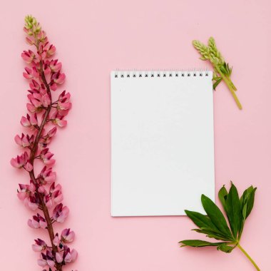 Çiçekler ve pembe bir arka plan üstünde defter kompozisyonu. Tasarımınız için alay. Düz yatıyordu.