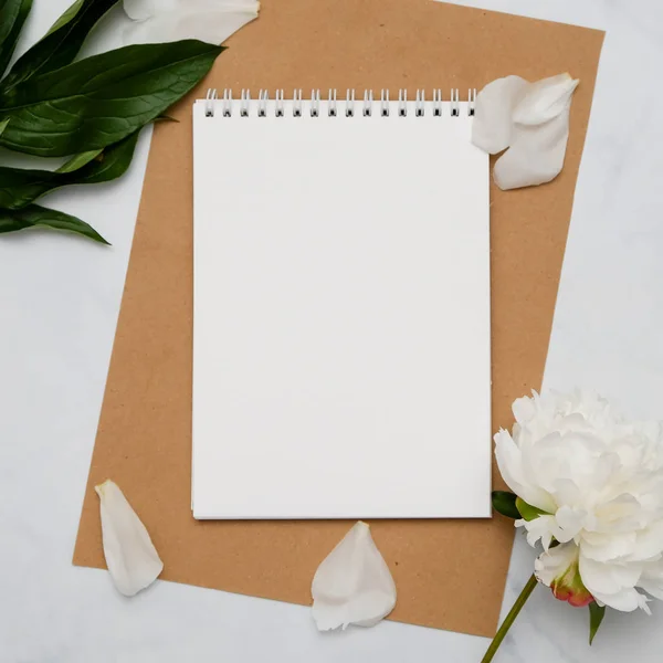 Composición con flores y cuaderno sobre fondo blanco. Prepárate para tu diseño. Puesta plana . — Foto de Stock