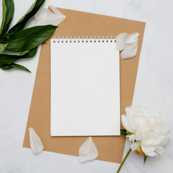 Composición con flores y cuaderno sobre fondo blanco. Prepárate para tu diseño. Puesta plana . — Foto de Stock