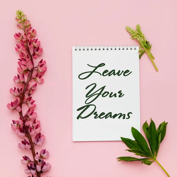 Çiçekler ve pembe bir arka plan üstünde defter kompozisyonu. Düz yatıyordu. İlham rüyalar terk.