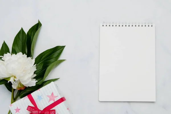 Composición con flores y cuaderno sobre fondo blanco. Prepárate para tu diseño. Puesta plana . — Foto de Stock