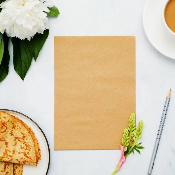 Composición con flor, panqueques, café y papel artesanal sobre fondo blanco. Prepárate para tu diseño. Puesta plana . — Foto de Stock