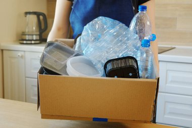 Plastik şişe ile bir karton tutan kadın geri dönüşüm için prepairing