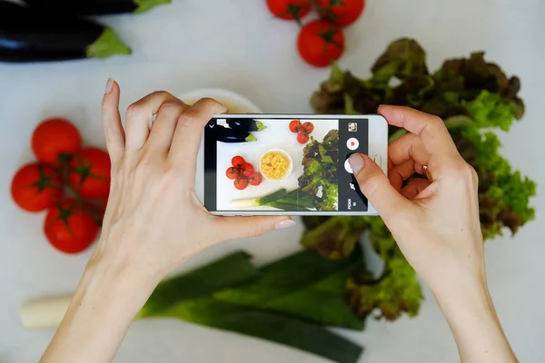 Food blogger concept. Hands with the phone close-up pictures of food. Top view.