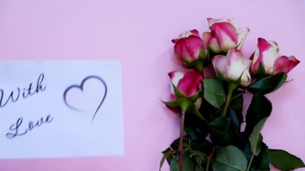 Met liefde wenskaart en bloemen op roze bord, top uitzicht — Stockvideo