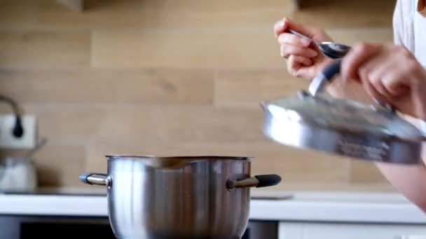Молода жінка готує і тестує занадто солону їжу на кухні — стокове відео