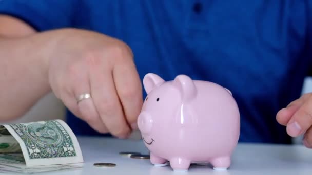 Hombre poniendo monedas en una alcancía — Vídeos de Stock