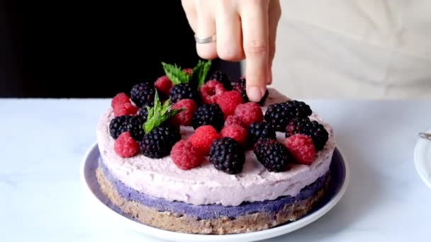Женщина украшает сырой веганский торт ягодами — стоковое видео