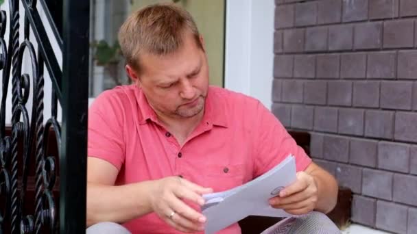 Choqué et contrarié jeune homme regardant le papier, les projets de loi — Video