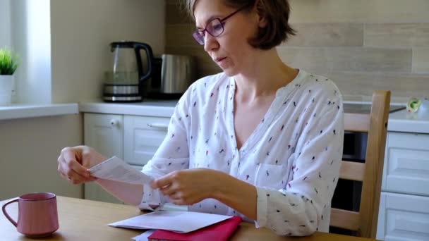Stress wegen Rechnungen. Unbeholfene Frau blickt in der Küche auf ihre finanziellen Schulden. — Stockvideo