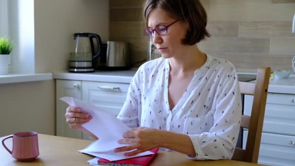 Stress wegen Rechnungen. Unbeholfene Frau blickt in der Küche auf ihre finanziellen Schulden. — Stockvideo