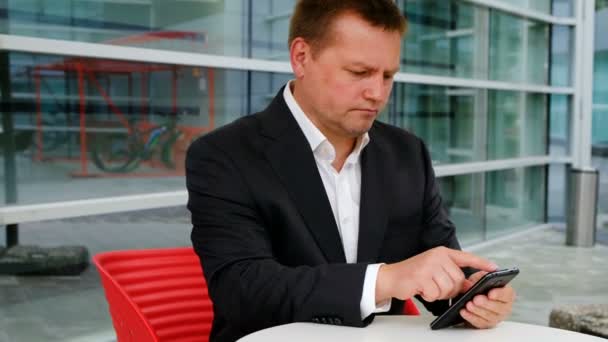 Junger selbstbewusster Geschäftsmann mit Smartphone draußen — Stockvideo