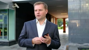 Dışarıda da telefonda konuşurken kendinden emin iş adamı