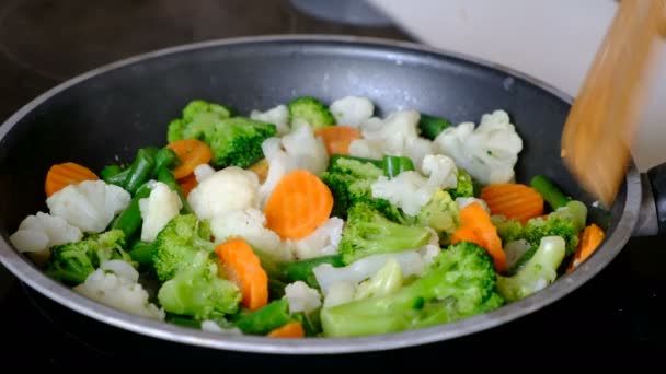 在黑暗的桌子上用锅搅拌油炸蔬菜, 关闭 — 图库视频影像