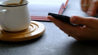 Smartphone kadının el, kahve ve defter bir tablo. Yakın çekim