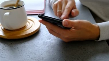 Smartphone kadının el, kahve ve defter bir tablo. Yakın çekim