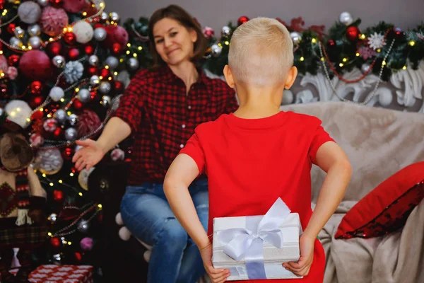 Moeder en kind met cadeaus in de buurt van de kerstboom thuis. Familie concept. — Stockfoto