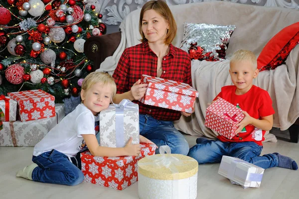 Moeder en kinderen met giften in de buurt van de kerstboom thuis. Familie concept. — Stockfoto