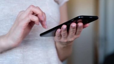 Modern cep telefonu ekran dokunaklı elinde olan kadın. Bir arka plan üzerinde bulanık ofis iç.