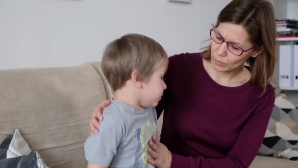 Милий маленький хлопчик кашляє, сидить зі своєю матір'ю у вітальні — стокове відео