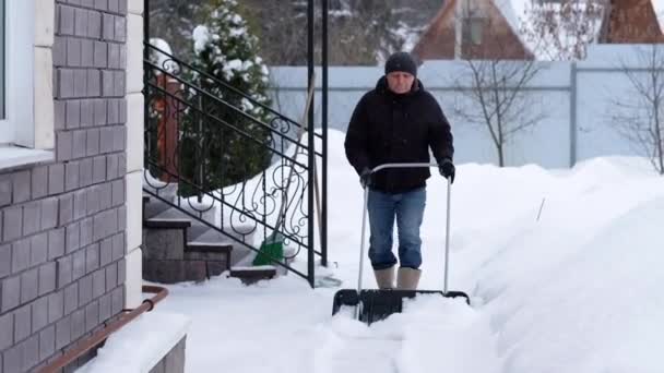 Vintern och rengöring koncept - mogen man skotta snön från uppfarten — Stockvideo