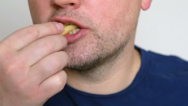 Un joven comiendo papas fritas. Concepto de comida rápida. De cerca. — Vídeos de Stock