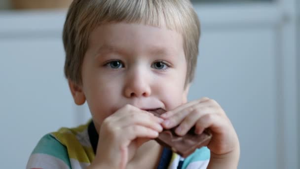 Rapaz bonito comendo chocolate, close-up — Vídeo de Stock