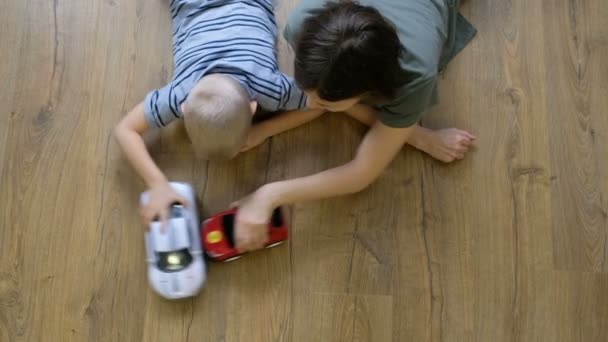 Concept de famille. Garçons et maman jouent avec des voitures sur le sol en bois. Père avec fils. Vue directement au-dessus — Video