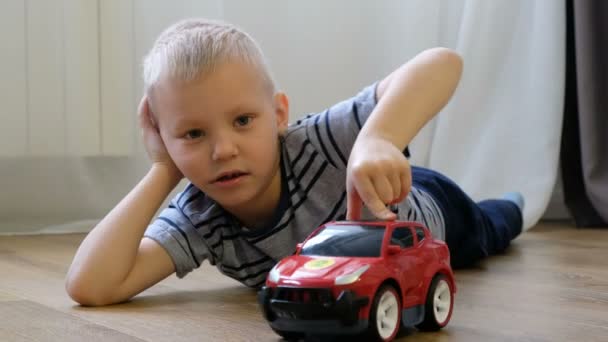 Schattige kleine jongen speelt met speelgoedauto thuis — Stockvideo