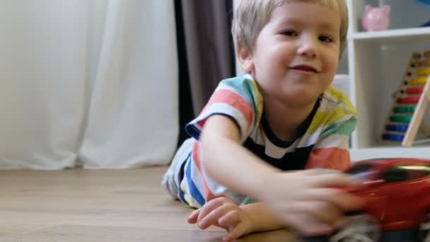 Cute little boy plays with toy car at home — Stock Video