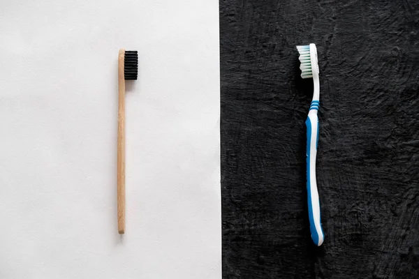 Kunststof versus bamboe tandenborstel op witte en zwarte achtergrond — Stockfoto