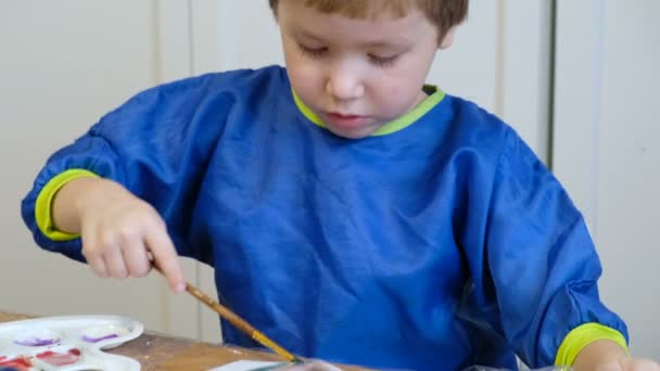 Leuke 4 jaar oude blonde jongen tekenen met gouache — Stockvideo