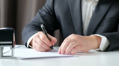 Yakın çekim işadamı el imzalama ve bir pul üzerinde belge ofiste basarak