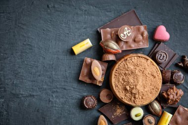 Siyah arka plan üzerine çeşitli çikolata ve kakao tozu