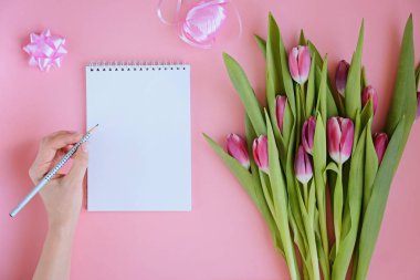 Çiçek, defter ve kadının elleri Pembe Lale ile kadınsı flatlay tarz