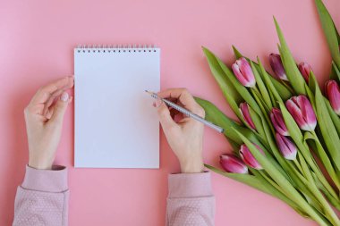 Pembe Lale ile kadınsı flatlay çiçek, defter ve kadının elleri tarz. Kopya alanı