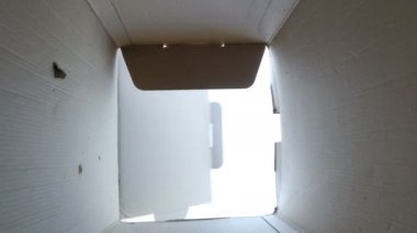 Küçük çocuk bir karton hediye, alt görünümü kadar açılarak