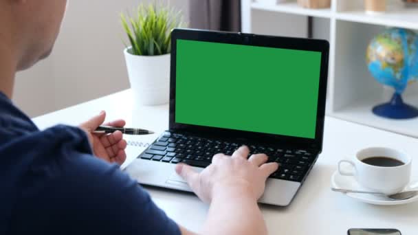 Hombre trabajando en una computadora, pantalla verde. Sobre el hombro disparado — Vídeos de Stock