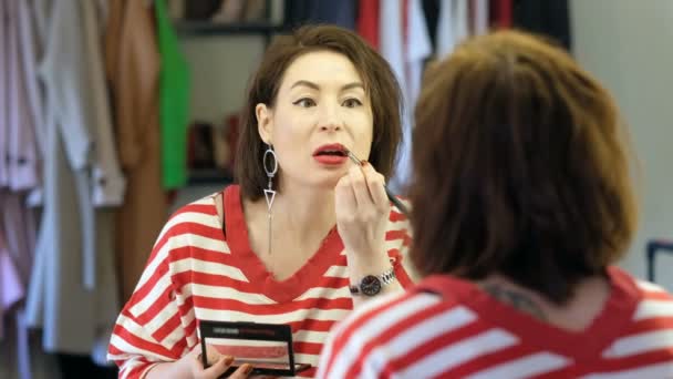Середнього віку красива жінка дивиться на дзеркало під час макіяжу — стокове відео