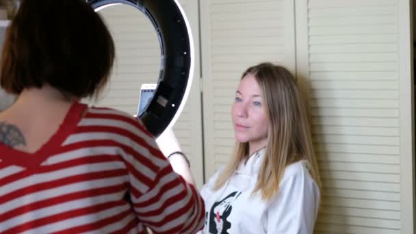 Kvinnan tar foto av en vacker flicka med mobiltelefon throung en ring led lampa — Stockvideo
