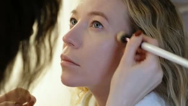 Επαγγελματική makeup artist που εργάζονται με όμορφη νεαρή γυναίκα — Αρχείο Βίντεο